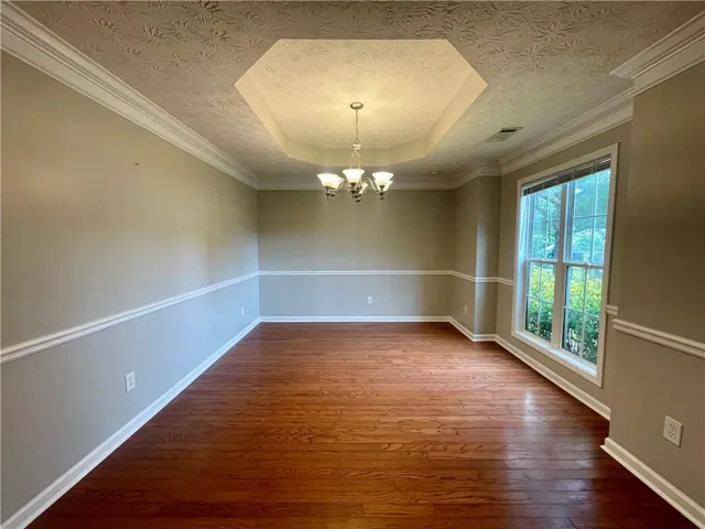 This spacious dining room features elegant crown molding and rich hardwood flooring, perfect for gatherings.