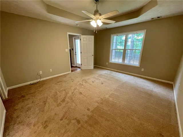 This spacious bedroom offers ample natural light and comfortable carpeting, perfect for relaxation.