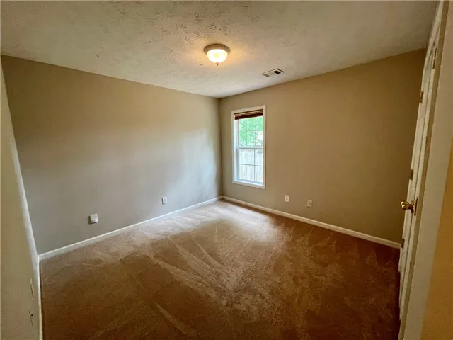 This spacious room offers comfort and versatility, featuring soft carpeting and natural light.