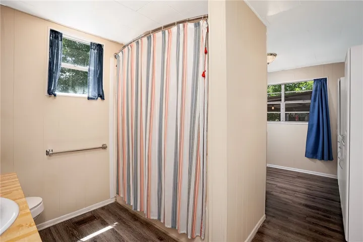 This bright bathroom features durable wood-look flooring and a window offering natural light.