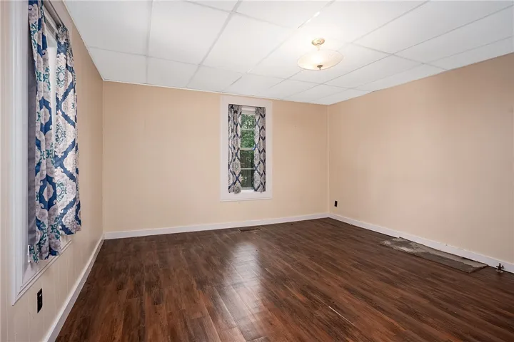 This versatile room features warm flooring and a large window, ready for your personal touch.
