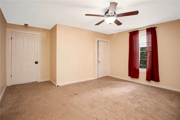 This cozy bedroom features a ceiling fan, plush carpeting, and natural light.