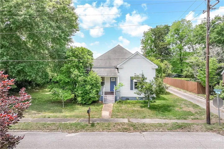 This charming home features a classic exterior and a welcoming front porch, nestled among mature trees.