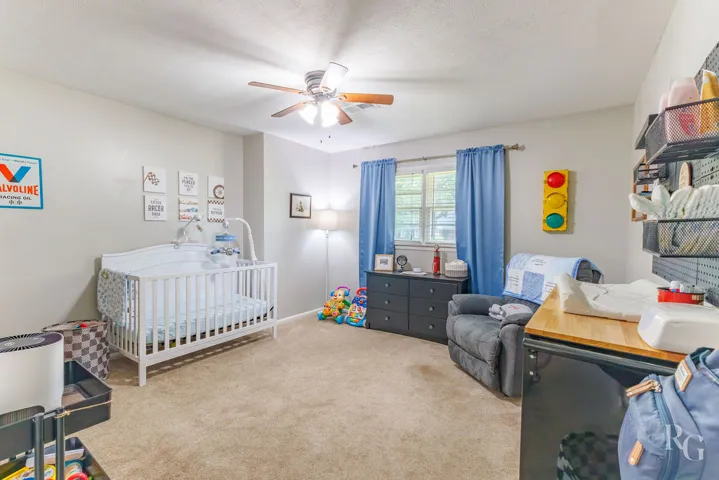 This cozy bedroom features plush carpeting and a convenient ceiling fan.