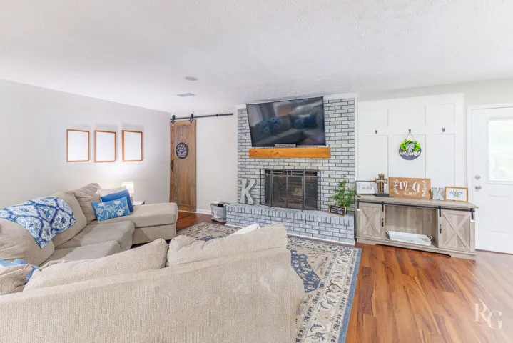 This inviting living space features hardwood flooring and a brick fireplace, creating a warm atmosphere.