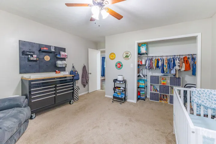 This cozy bedroom features comfortable carpeting and a convenient open closet area, perfect for a child's sanctuary.