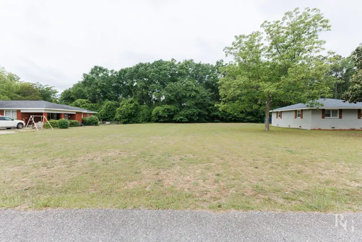 Expansive lawn with mature trees and traditional brick architecture offers serene outdoor living.