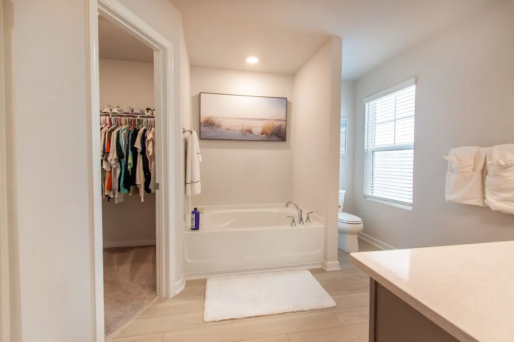 This serene bathroom offers a soaking tub and a spacious walk-in closet for ultimate comfort.
