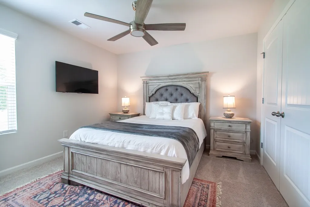 This inviting bedroom features soft carpeting and a ceiling fan, creating a comfortable and relaxing atmosphere.