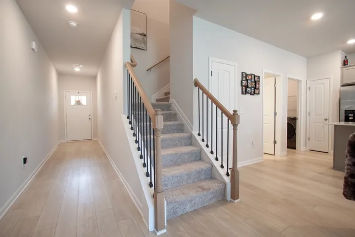 This inviting entryway features light wood flooring and a staircase with a modern railing.