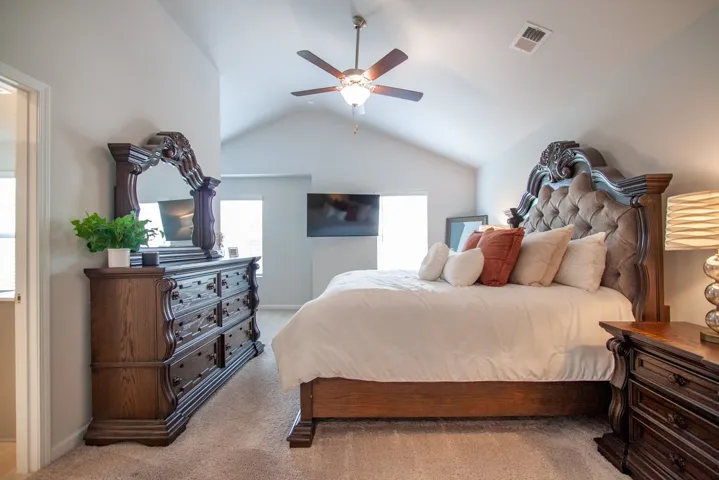 This primary bedroom features vaulted ceilings and ample natural light, creating an airy and open ambiance.