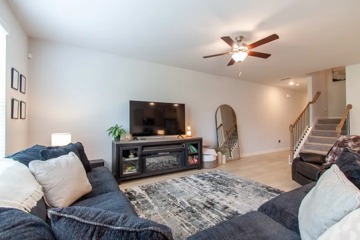 This inviting living space features an open layout, durable flooring, and convenient access to the staircase.