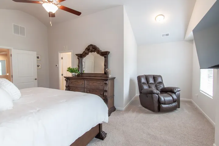 This spacious bedroom features vaulted ceilings and carpeted flooring, perfect for comfortable living.