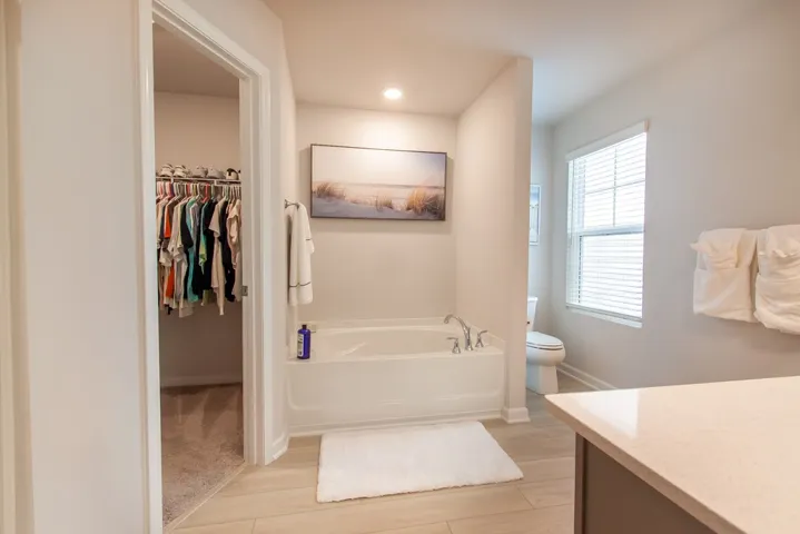 This serene bathroom offers a soaking tub and a spacious walk-in closet for ultimate comfort.