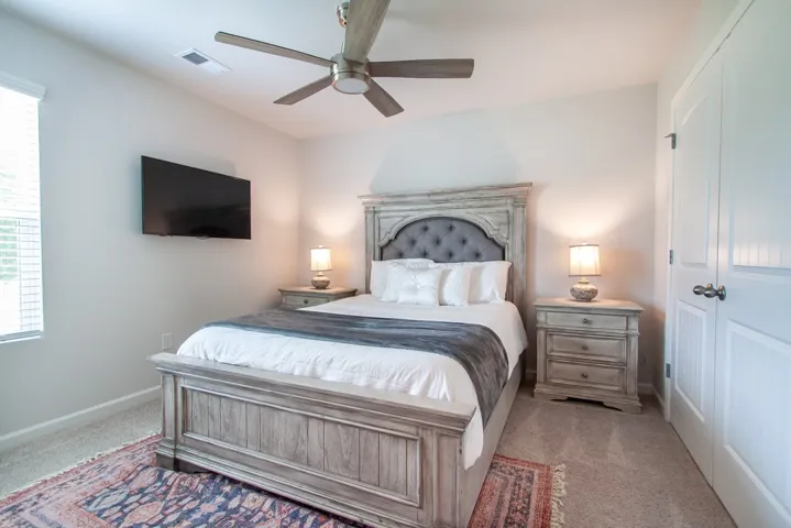 This inviting bedroom features soft carpeting and a ceiling fan, creating a comfortable and relaxing atmosphere.