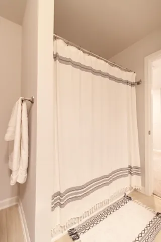 This clean bathroom showcases a pristine shower area with light-toned flooring.