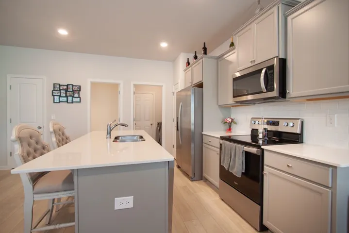 This kitchen features sleek countertops, a functional island with a sink, and modern appliances, creating an inviting culinary space.