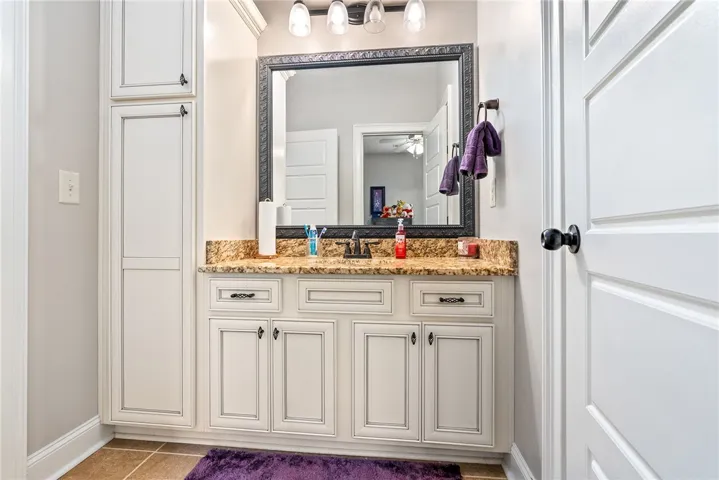This clean and functional bathroom features a single vanity, ample storage, and tiled flooring.