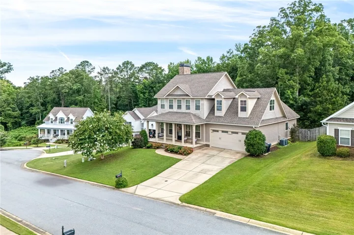 This spacious residence features a welcoming covered porch, attached garage, and a lush, well-maintained lawn.