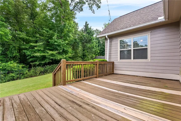 This spacious wooden deck overlooks a verdant backyard, perfect for outdoor enjoyment and relaxation.