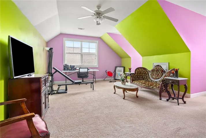 This versatile bonus room features soft carpeting and ample natural light from large windows.