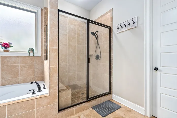 This bathroom offers a spacious shower and a soaking tub, perfect for unwinding.