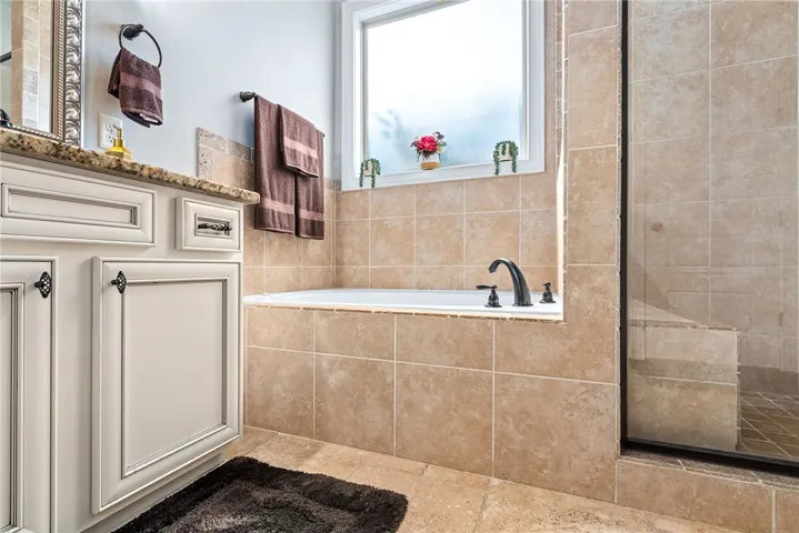 This bathroom features a deep soaking tub and a tiled shower, offering a blend of comfort and design.