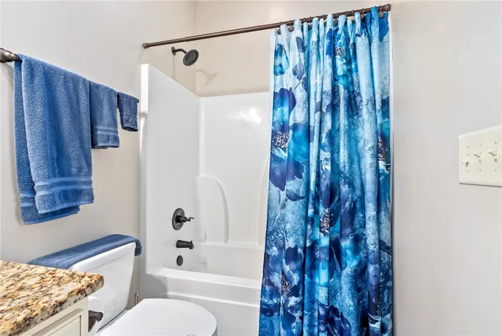 This bright bathroom features a spacious tub and shower combination, complete with modern fixtures.