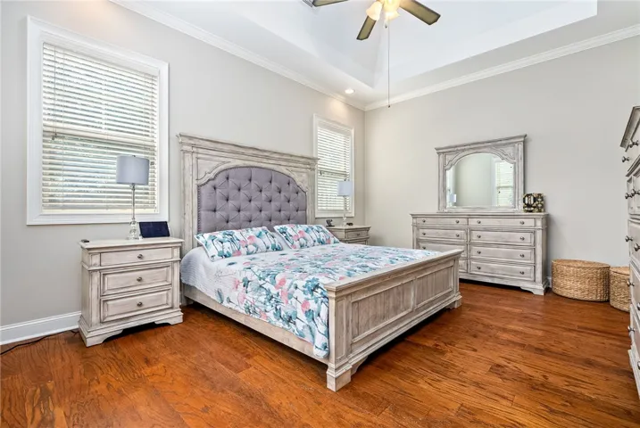 This primary bedroom features high ceilings, hardwood flooring, and ample natural light.