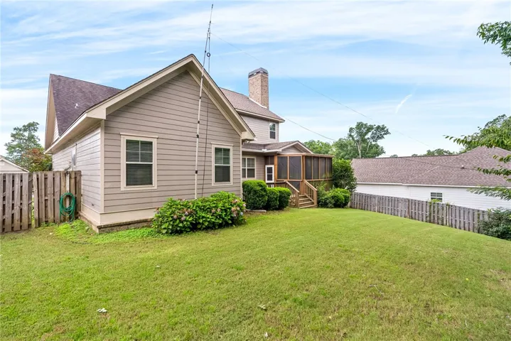This residence showcases a spacious lawn with privacy fencing and a charming screened porch.