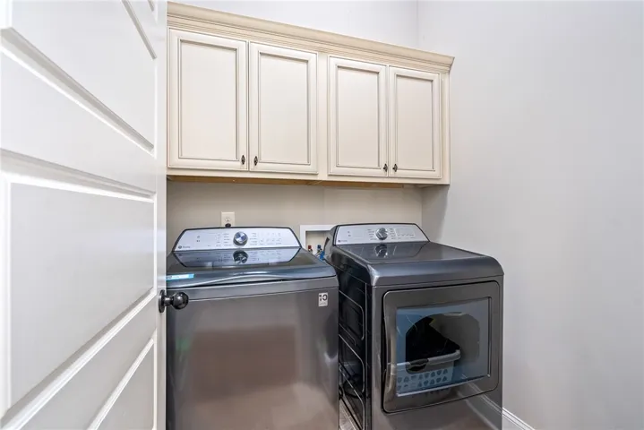 This dedicated laundry space features convenient storage cabinetry above modern washer and dryer units.