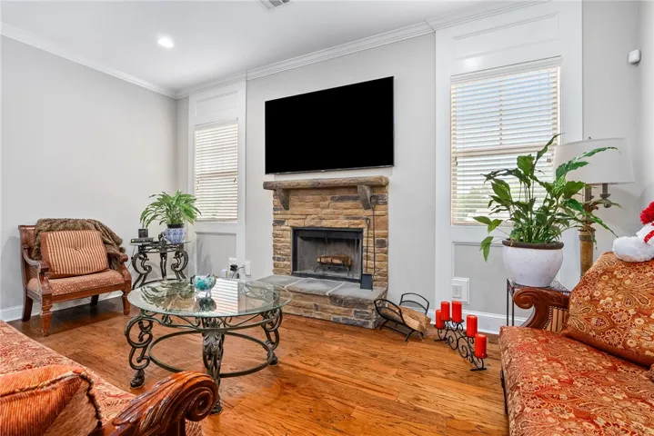 This inviting living area features warm wood flooring and a classic stone fireplace, perfect for gatherings.