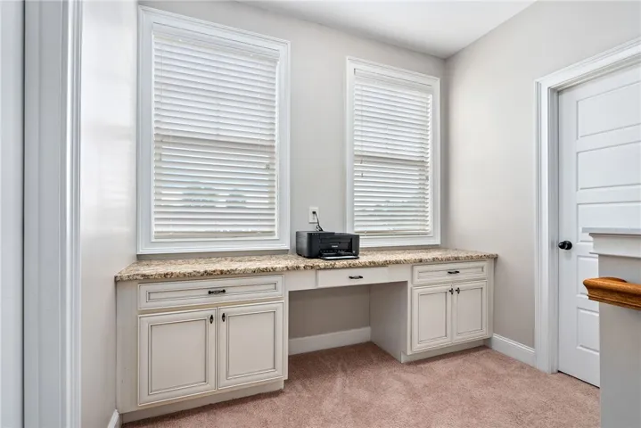 Functional office space features granite counters and carpet flooring, offering a versatile work area.