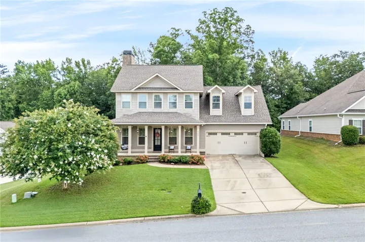 This two-story home features a welcoming porch, a convenient attached garage, and well-maintained landscaping.