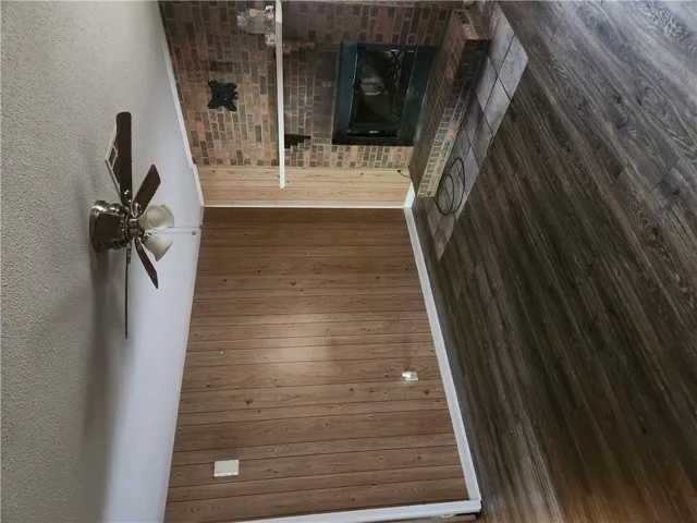 This living area features rich wood flooring and a classic brick fireplace, creating a cozy ambiance.