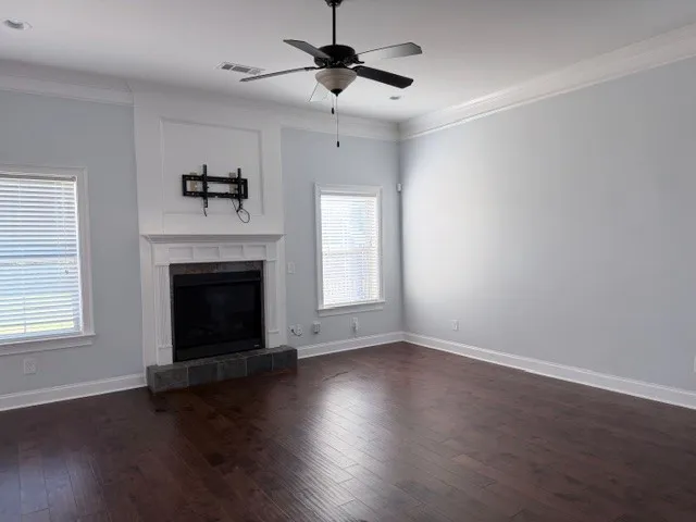 This inviting room features elegant crown molding, rich hardwood floors, and a charming fireplace, perfect for gatherings.