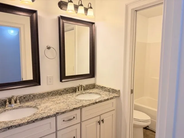 This bathroom features a double vanity with ample counter space, reflecting light and offering practical elegance.