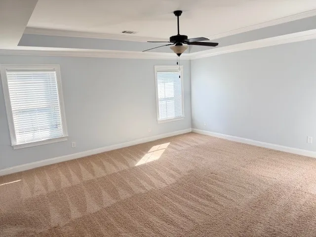 This spacious bedroom offers comfortable carpeting and elegant tray ceilings, perfect for serene living.