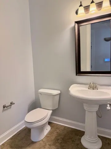 This practical bathroom features a sleek toilet and a charming pedestal sink, offering functional simplicity.