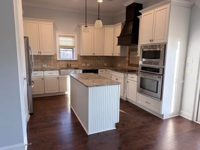 This bright kitchen offers a large island, stainless steel appliances, and ample cabinet space for culinary endeavors.