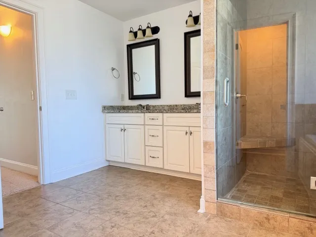 This spacious bathroom offers elegant dual vanities and a large walk-in shower.