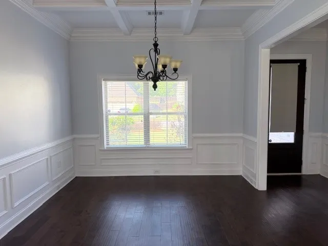 This elegant space showcases rich wood flooring and classic wainscoting, perfect for formal gatherings.