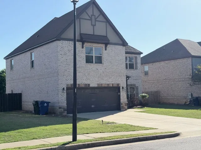 This two-story residence features a brick facade and a well-maintained driveway.