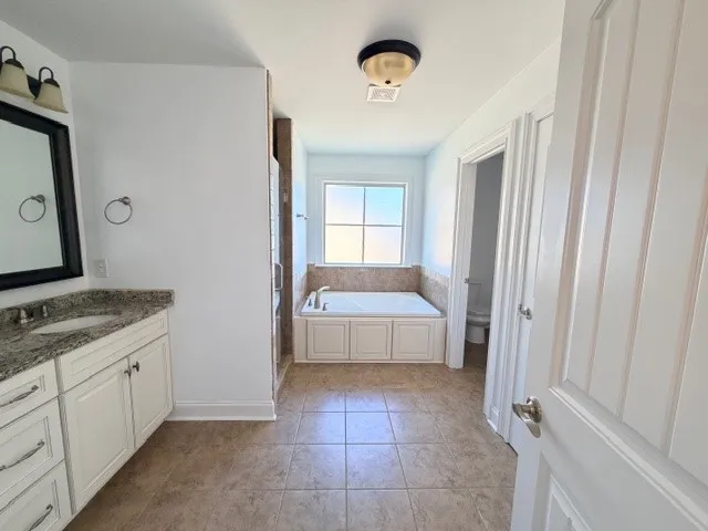 This spacious bathroom offers a relaxing soaking tub and ample counter space, creating a serene retreat.