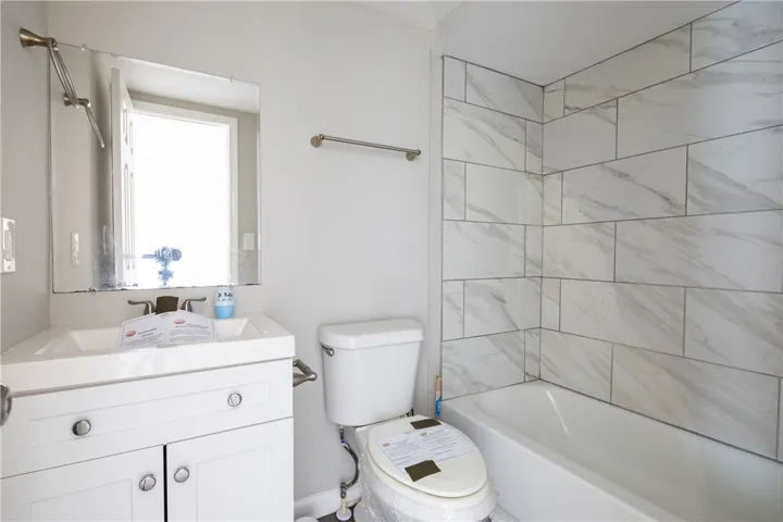 This newly updated bathroom features a sleek vanity and a tiled bath for modern comfort.