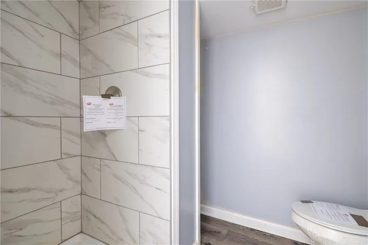 This bright bathroom features a sleek shower and elegant flooring.