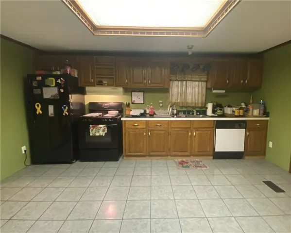 This kitchen features classic cabinetry, a ceiling light fixture, and tile flooring.