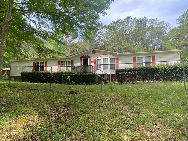This inviting home features a charming exterior with bay windows and a fenced yard.