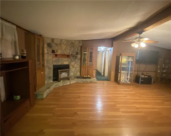 This inviting space features a captivating stone fireplace and warm wood flooring.