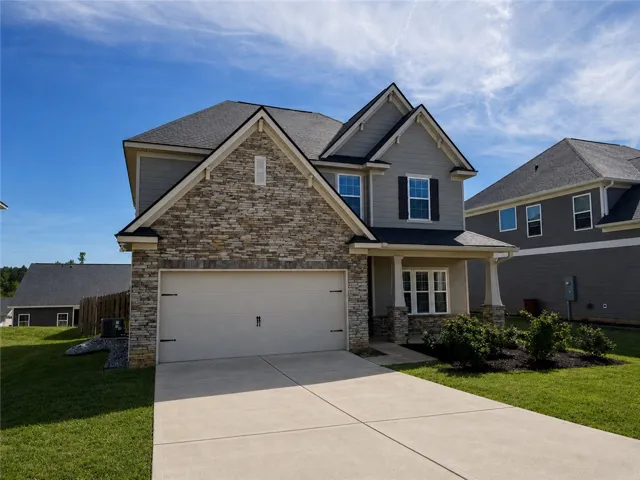 This charming home offers a two-story design with a concrete driveway and an attached garage.